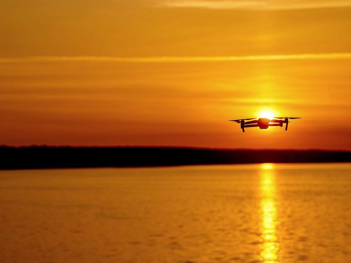 Gün batımında su üzerinde havada duran drone